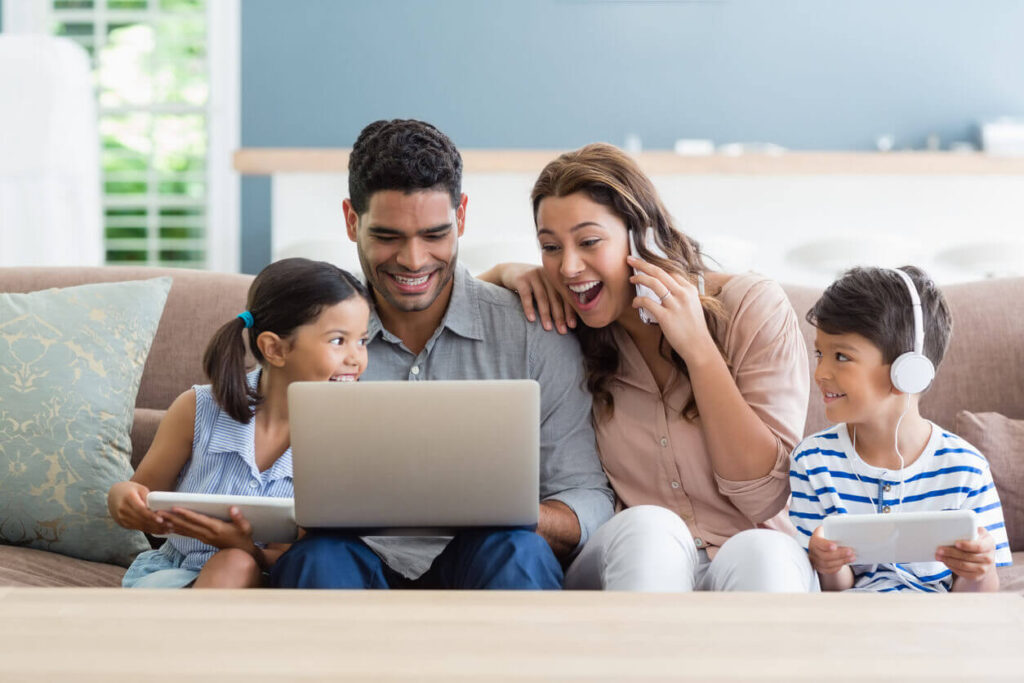 Parents and kids using laptop and digital tablet in living room