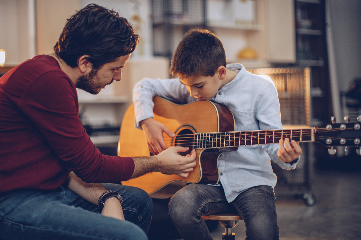 Boy teaching to play guitar in music school