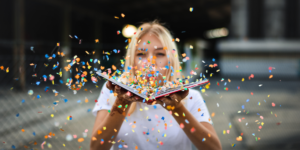A woman blowing confetti out of an open book