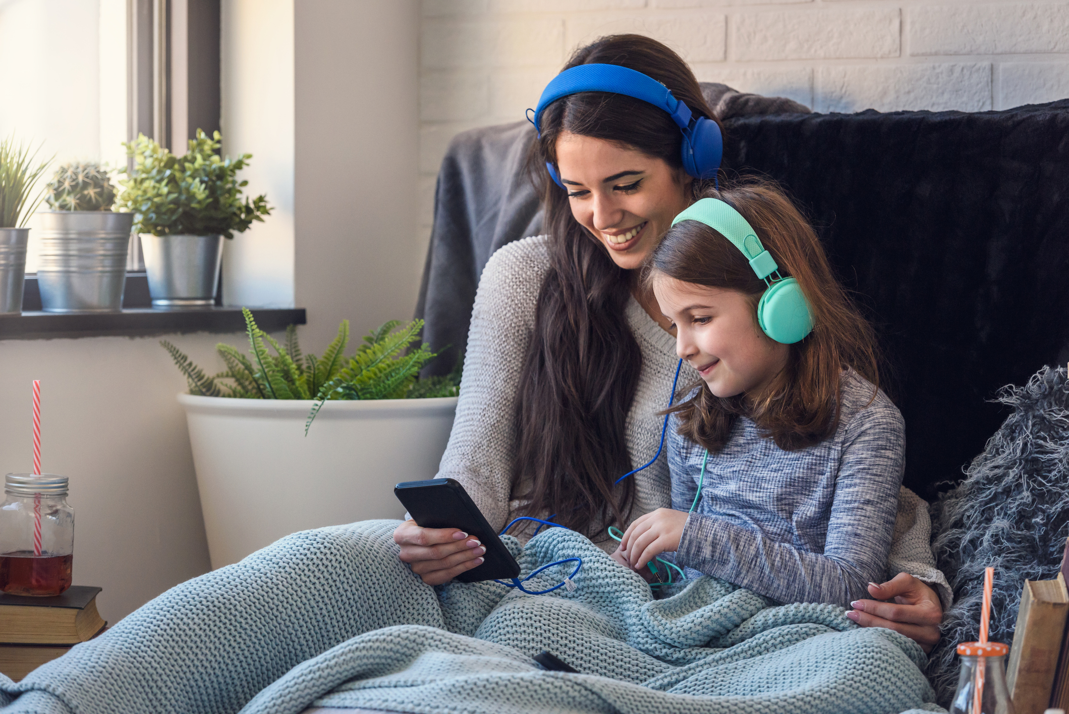 Mother and daughter having fun with smart phone and headphones