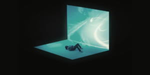 Seph Schlueter laying on his back in a blue shape where it looks like he's in a 3D water-type page while the rest of the surroundings are a void.